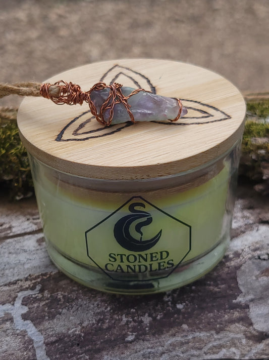 Candle with wooden lid featuring a decorative stone and 'Stoned Candles' branding.