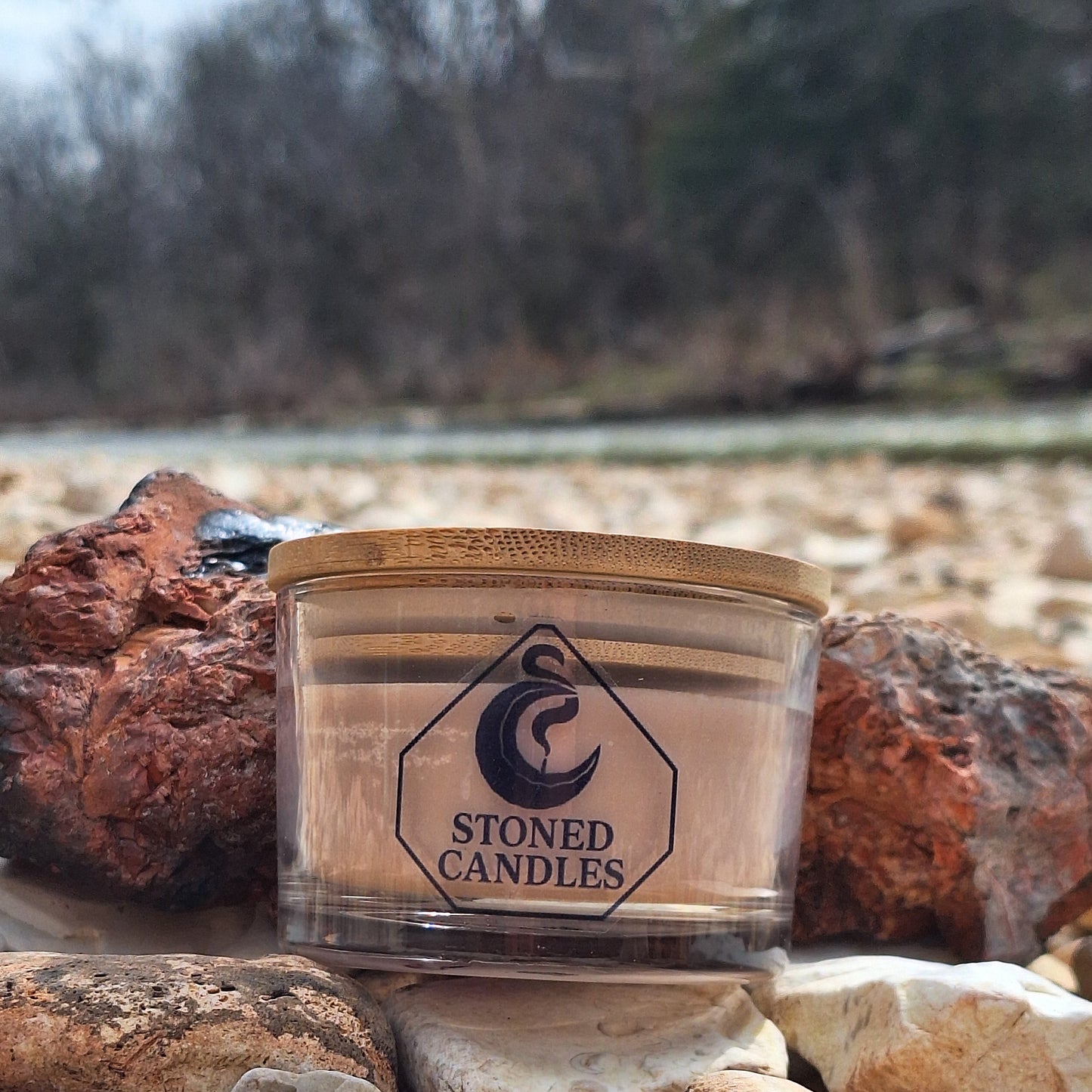 Candle in a wooden holder against a stone wall with a blurred natural background
