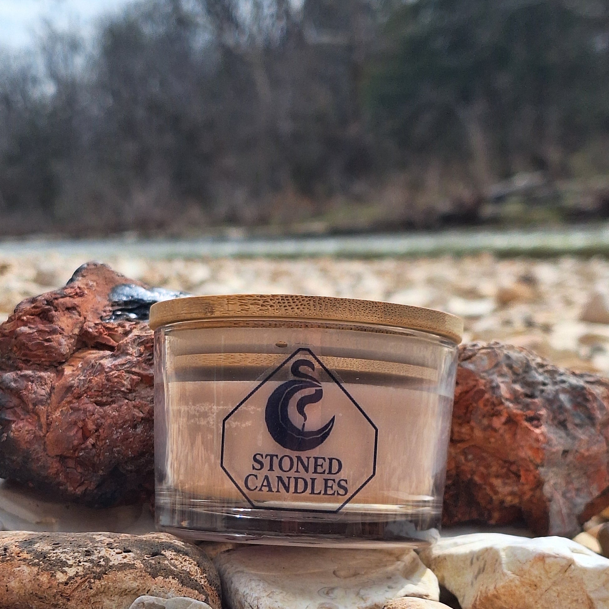 Candle in a wooden holder against a stone wall with a blurred natural background