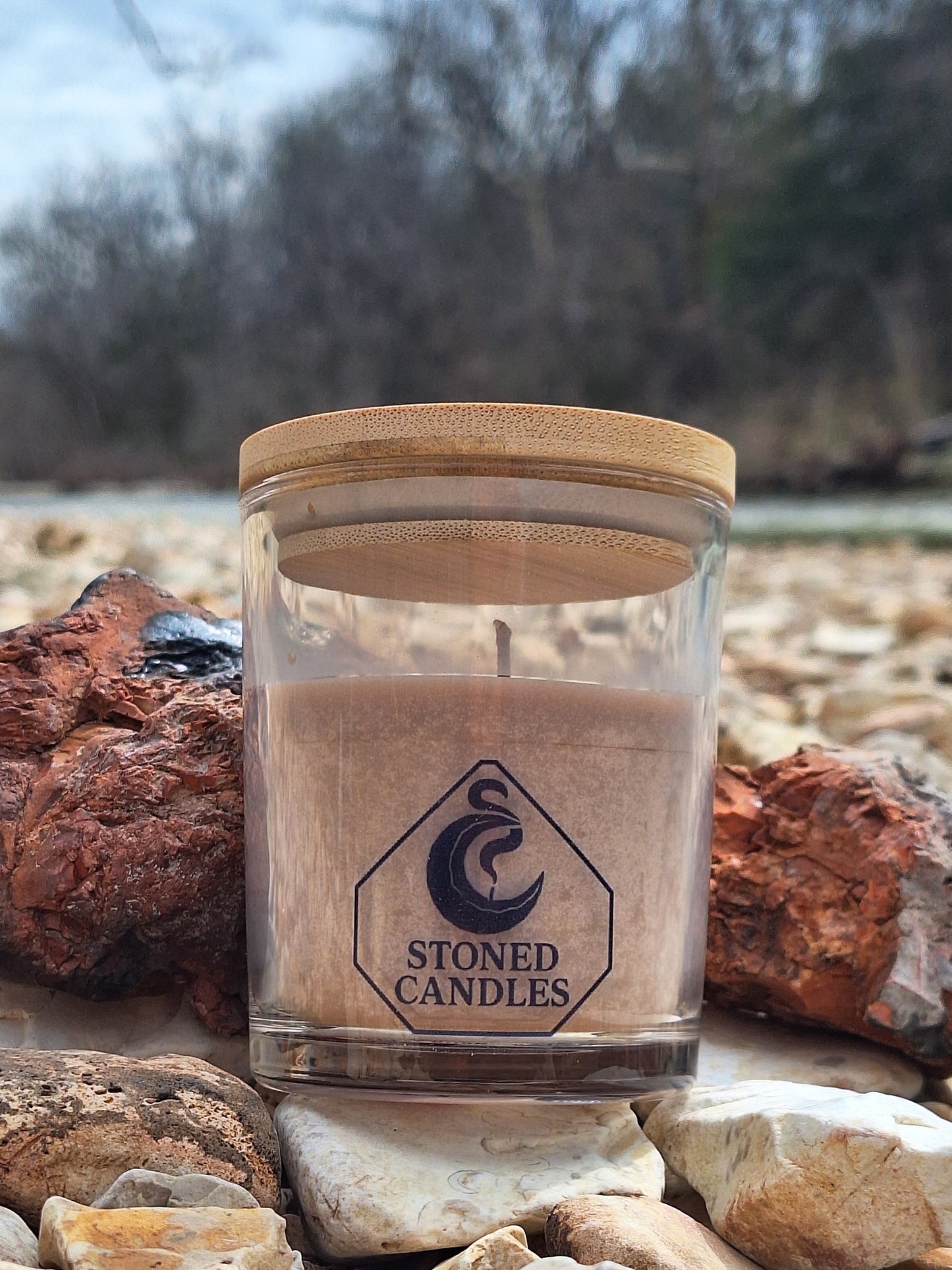 Candle jar with wooden lid on a rocky surface