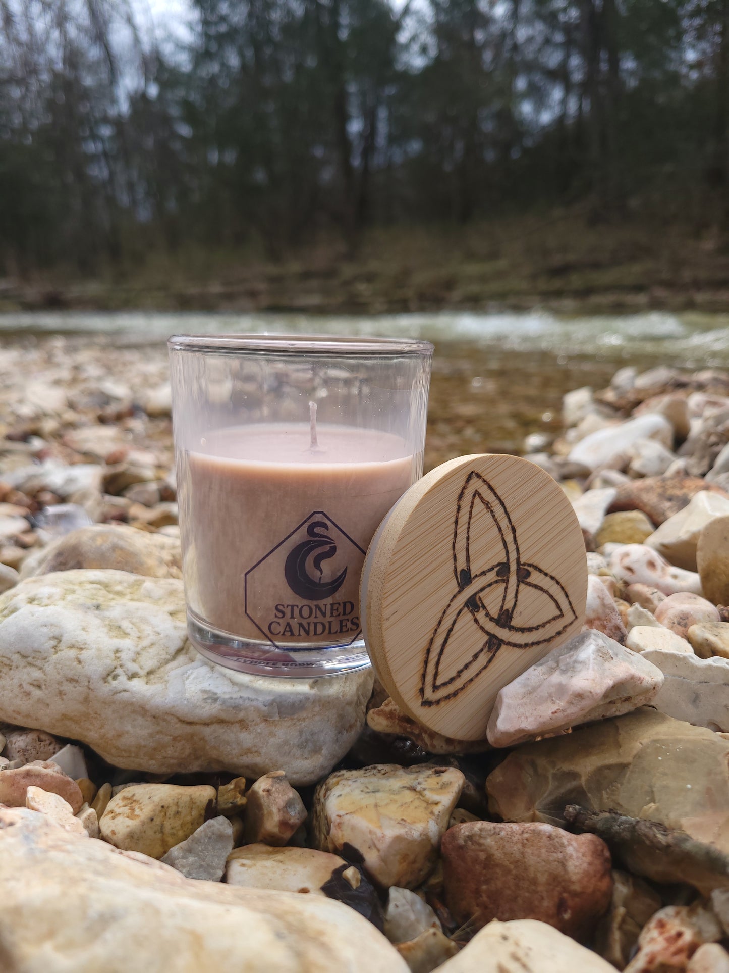 Glass bottle with wooden cap on a rocky surface near water