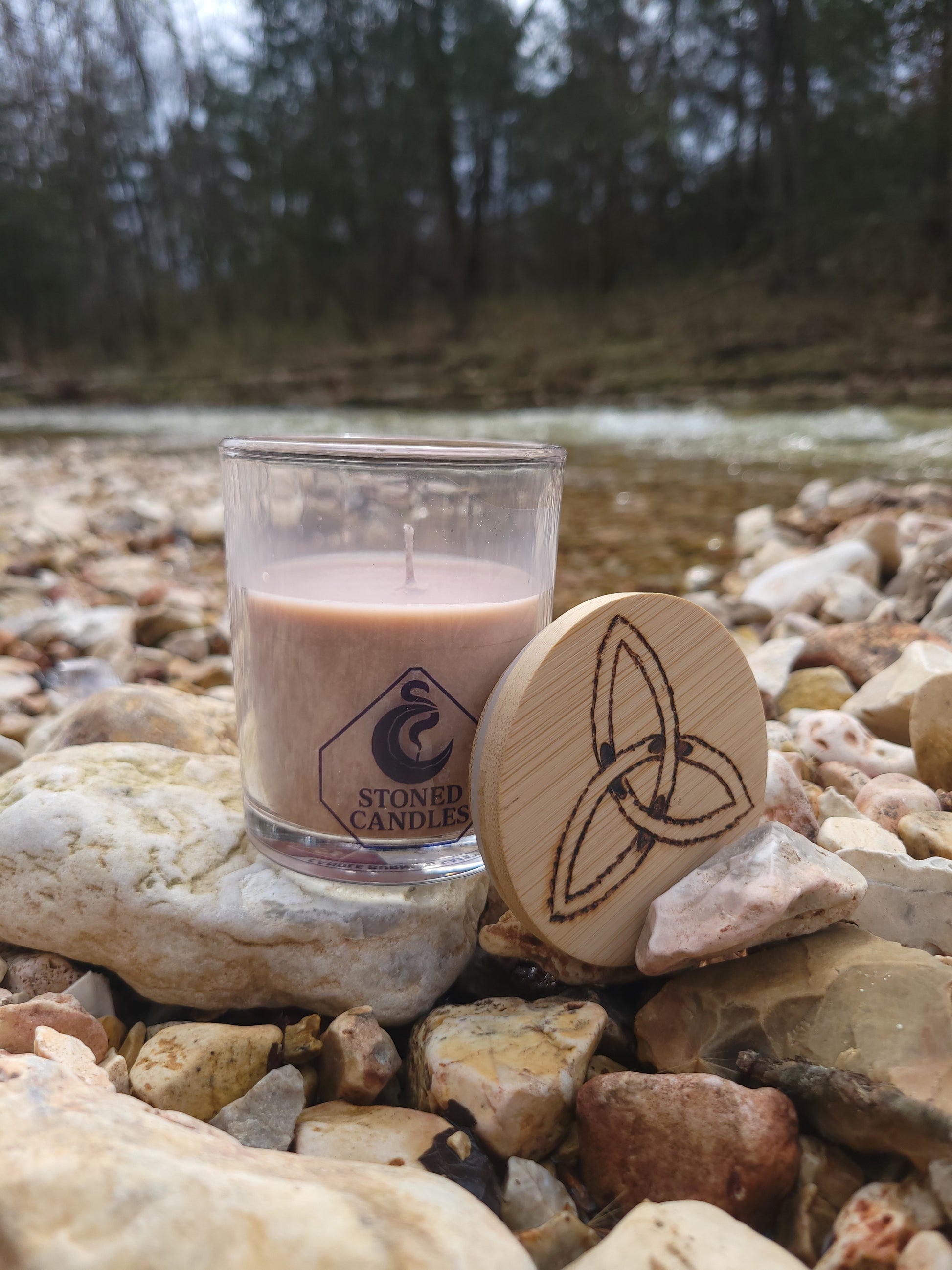 Glass bottle with wooden cap on a rocky surface near water