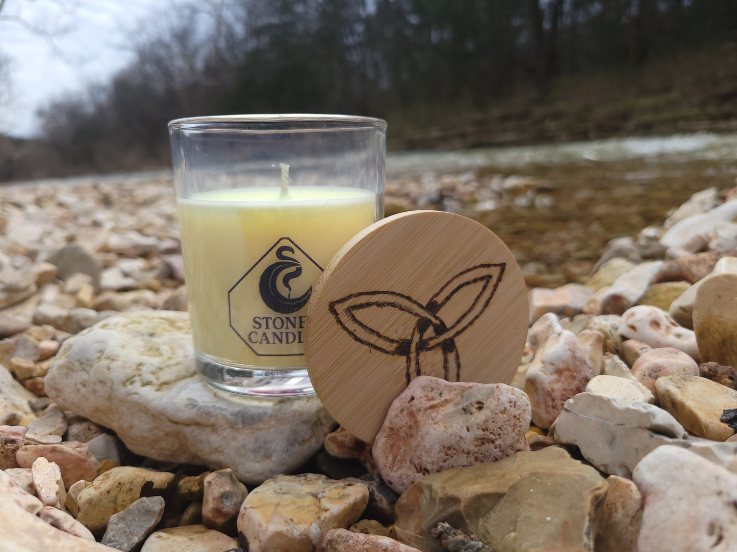 Small glass candle with wooden lid on a stone surface