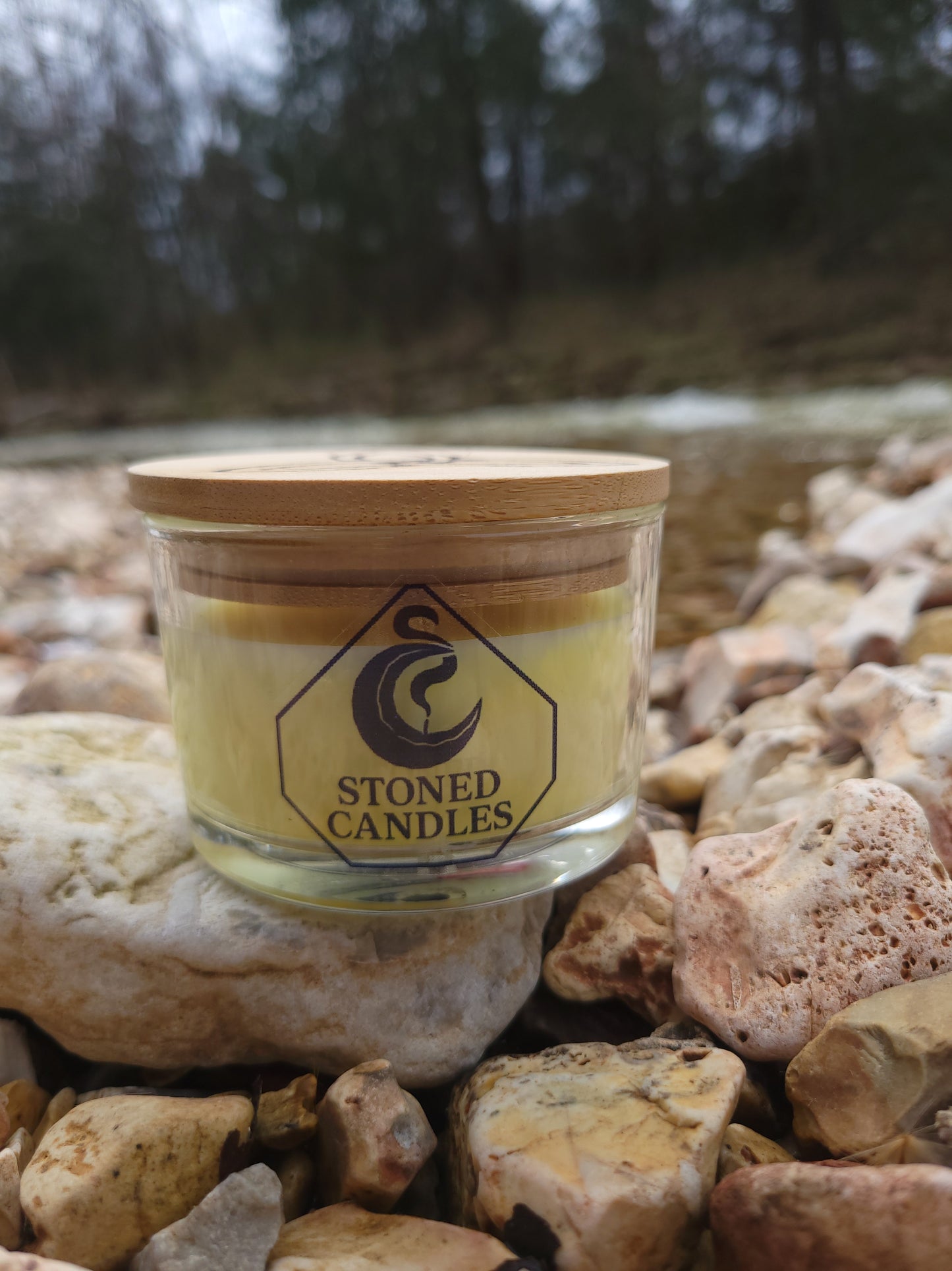 Jar of 'Stoned Candles' on a rocky surface with blurred natural background
