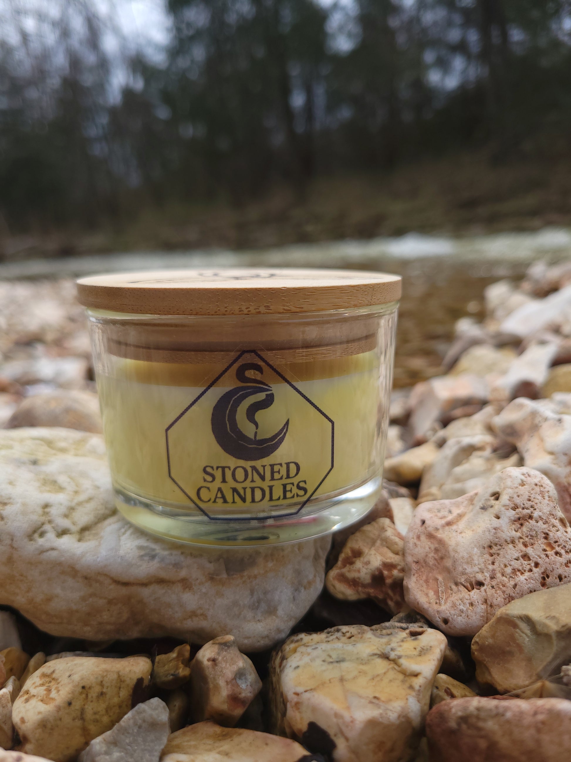 Jar of 'Stoned Candles' on a rocky surface with blurred natural background