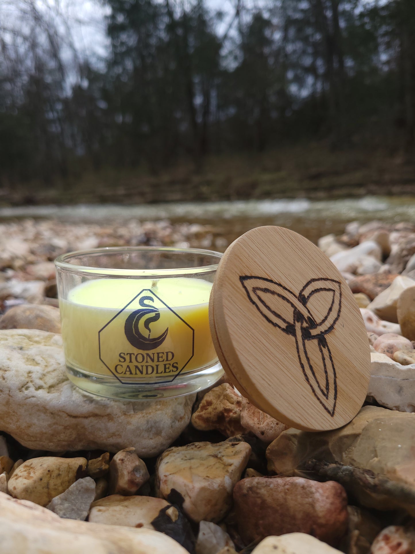 Glass candle holder with wooden lid on a stone surface