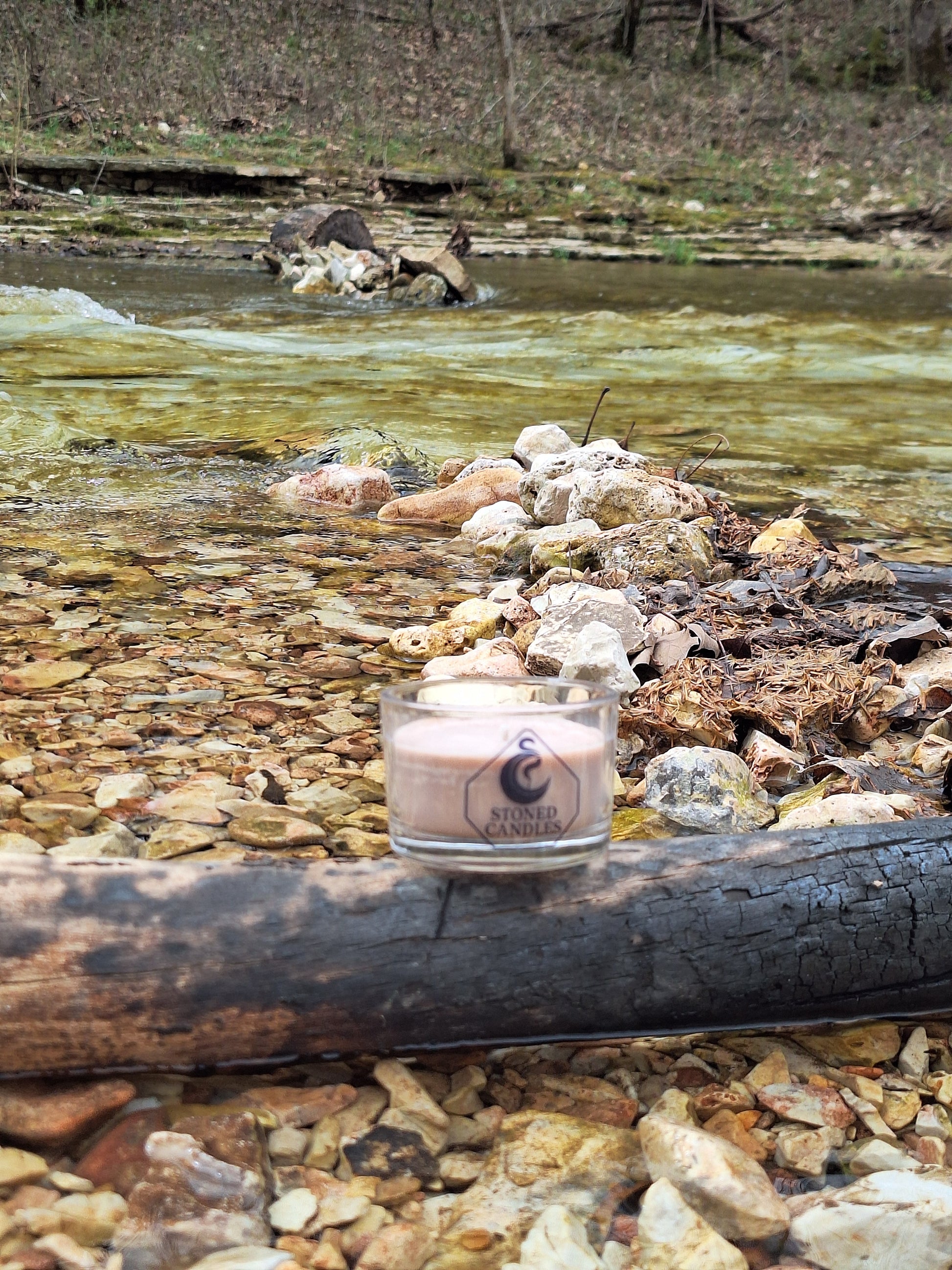 Candle with a photo inside on a rocky surface near water