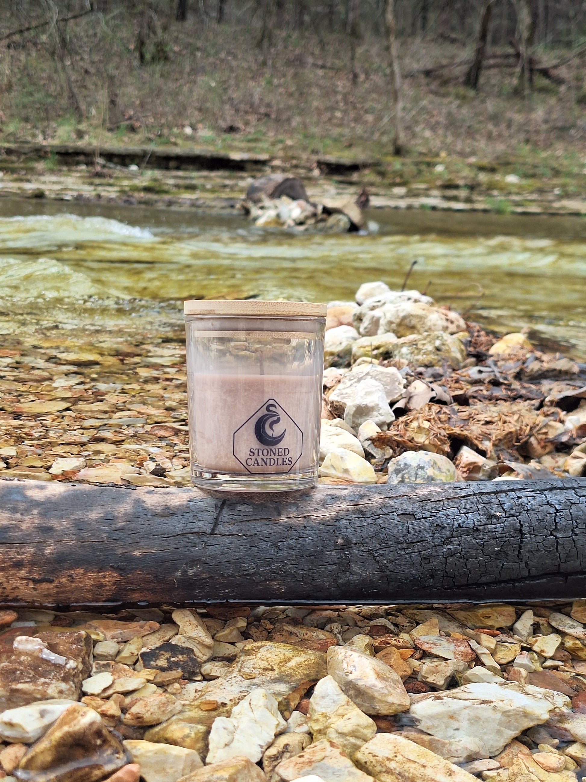 Clear glass tumbler with a logo on a rocky surface